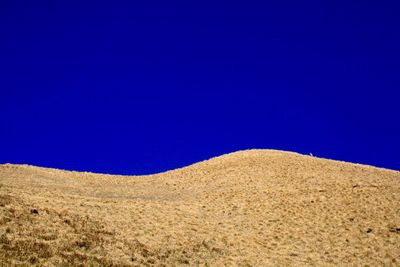 Scenic view of desert against clear blue sky