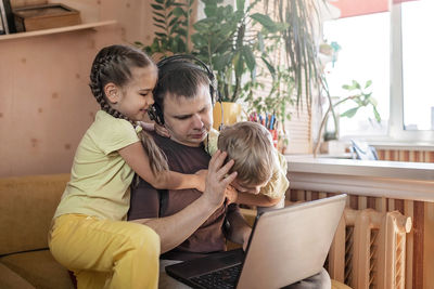 Rear view of man using phone while sitting at home