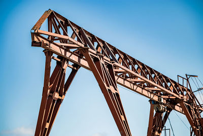 Low angle view of crane against clear blue sky