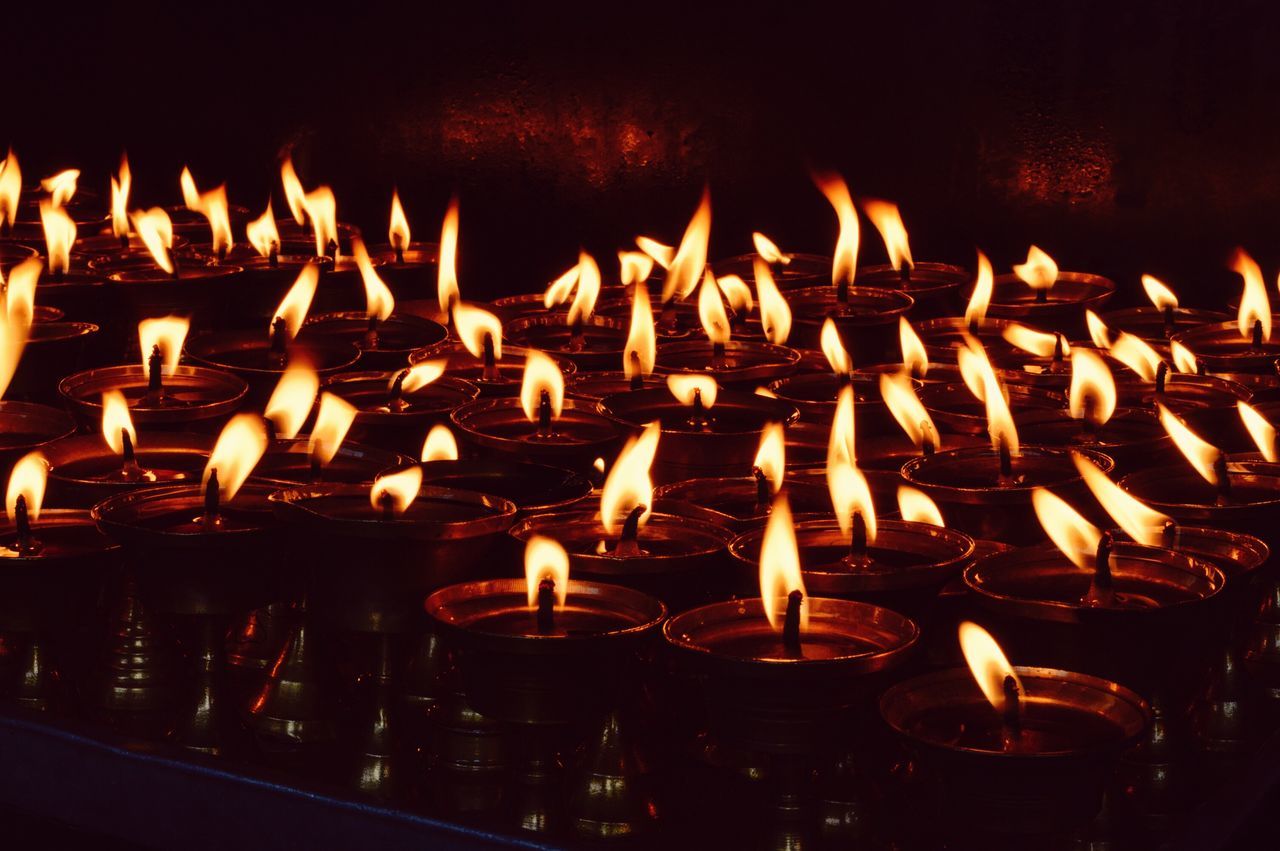 burning, illuminated, flame, night, glowing, heat - temperature, fire - natural phenomenon, candle, indoors, in a row, lit, large group of objects, dark, repetition, close-up, candlelight, fire, abundance, light - natural phenomenon, no people