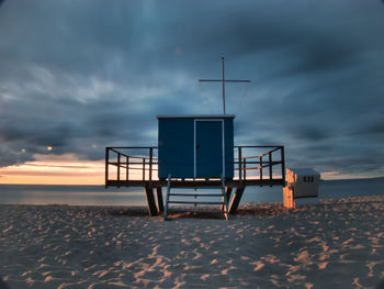 Lifeguard hut on beach against sky during sunset