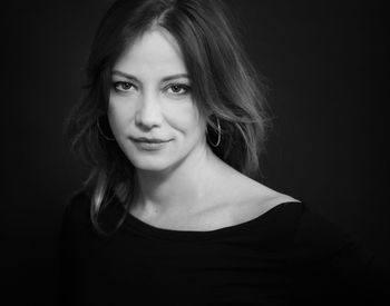 Portrait of smiling young woman against black background