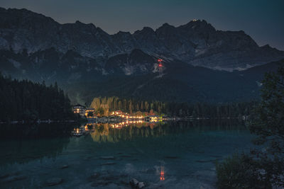 Scenic view of lake and mountains against sky at night