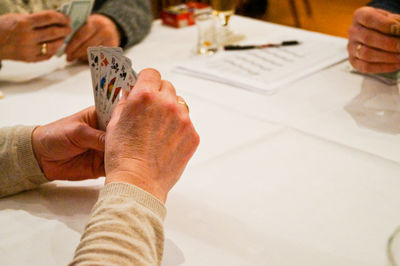 Cropped image of friends playing cards on table