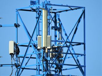 Low angle view of electricity pylon against clear blue sky