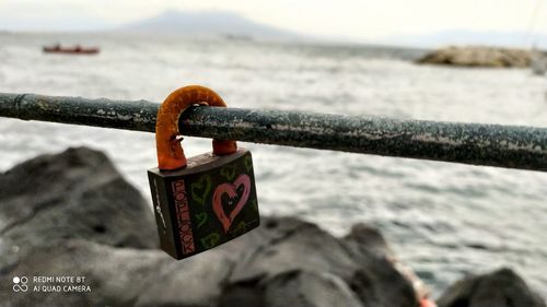 Close-up of padlocks on railing against sea