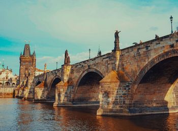 Arch bridge over river against sky in city