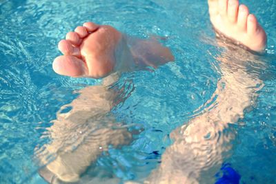 Low section of person swimming in pool