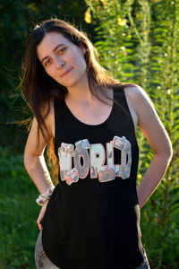 Portrait of confident young woman standing with hands on hips at park