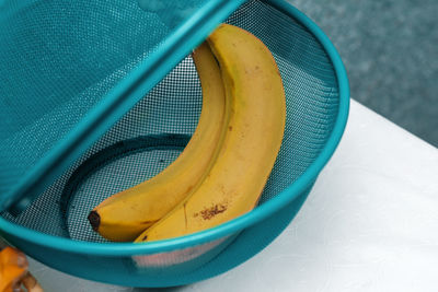 Two yellow bananas in a basket on the kitchen table