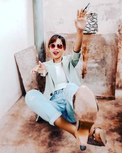 Portrait of young woman sitting with arms raised