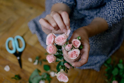 Midsection of woman plucking petals from rose at home