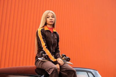 Young african american woman with long blonde hair and sportswear on an orange background