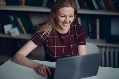 Mid adult woman using mobile phone while sitting on table