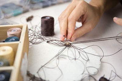 Close-up of hand holding thread on table