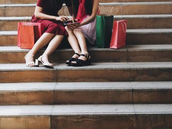 Low section of friends using digital tablet on steps