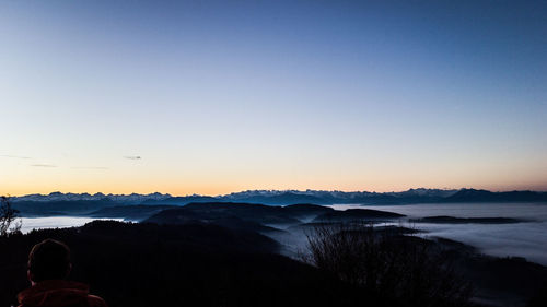 Silhouette man on mountain against clear sky during sunset