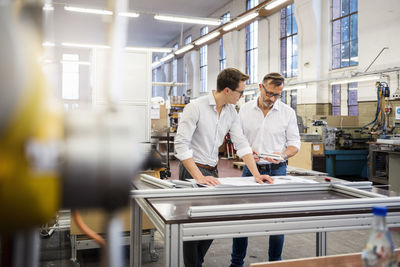 Two businessmen in factory discussing plan