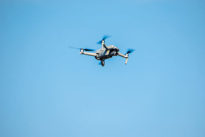 Low angle view of airplane flying against clear blue sky