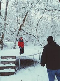 Rear view of people on snow covered plants during winter