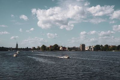 Scenic view of river by buildings against sky