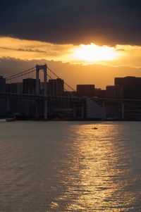 Scenic view of sea by buildings against sky during sunset