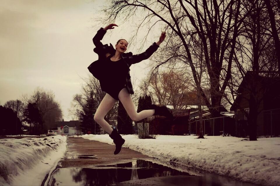 full length, lifestyles, leisure activity, young adult, person, jumping, mid-air, casual clothing, young men, enjoyment, front view, arms outstretched, sky, side view, skill, tree, winter, fun