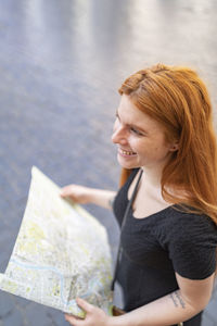 Happy woman hold a city map smiling outdoor in a sunny day