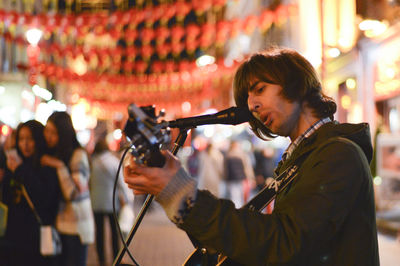 Side view of man playing music at night