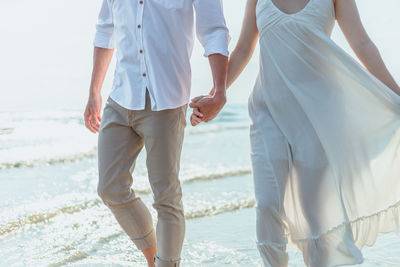 Rear view of couple walking on beach