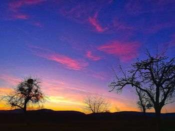 Silhouette trees on field against romantic sky at sunset