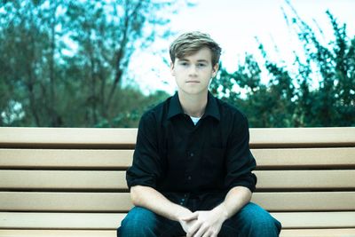 Mid adult man sitting against trees