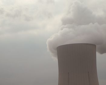 Low angle view of smoke emitting from factory against sky