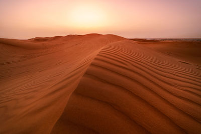 Sand dunes in desert against sky during sunset