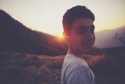 Portrait of boy standing on mountain against sky during sunset