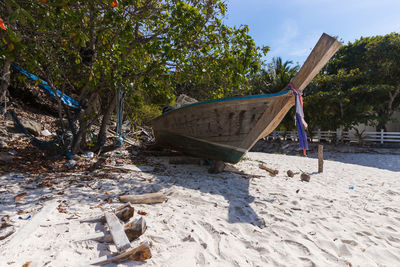 Abandoned boat moored on shore against sky
