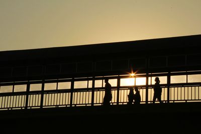 Low angle view of silhouette people standing by railing against clear sky