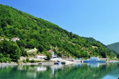 Scenic view of lake and mountains against clear blue sky