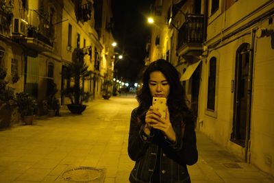 Portrait of young woman standing on street at night