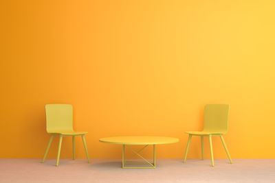 Empty chairs and table against on floor against wall