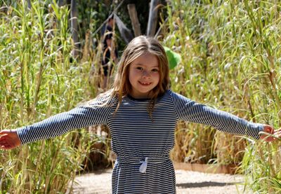 Portrait of girl standing with arms outstretched on field