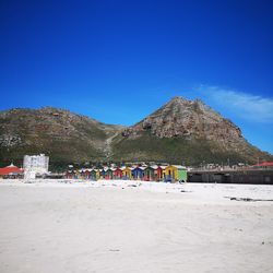 Group of people on beach against clear blue sky