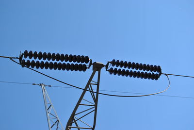 Low angle view of electricity pylon against clear sky