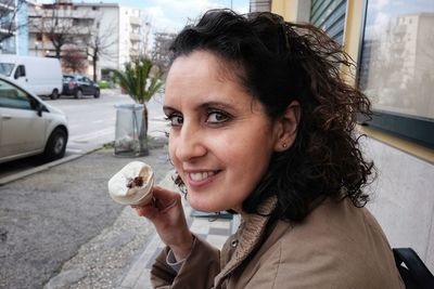 Close-up portrait of woman eating ice cream cone on sidewalk