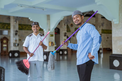 Portrait of men holding mop at mosque