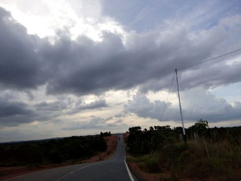 Empty country road against cloudy sky