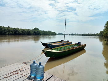 Boat moored on lake against sky