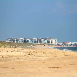 Beach by buildings against clear blue sky