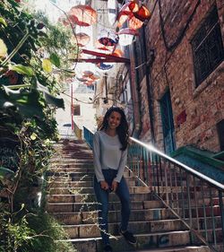 Portrait of young woman on staircase against building