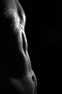 Close-up of shirtless man against black background
